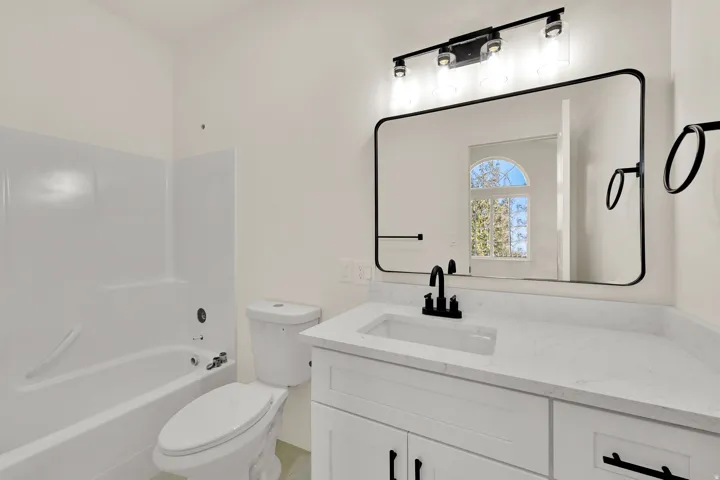White vanity with black hardware, rectangular undermount sink, and light-toned countertop