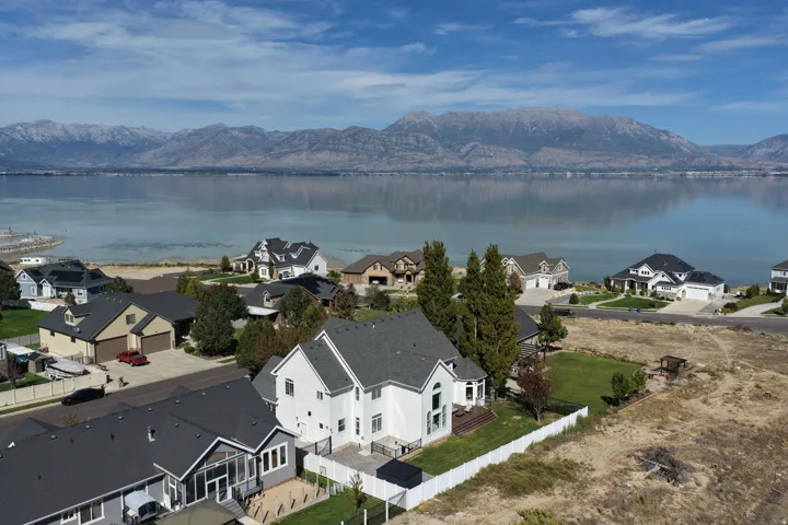 Lakefront property with mountain backdrop, established landscaping, and multi-level decks