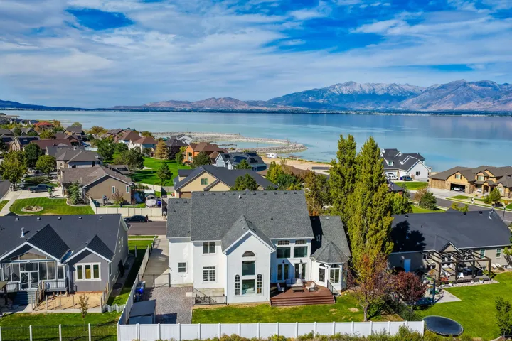 Lakefront property featuring a two-story residence with an expansive backyard, large deck, and mature trees
