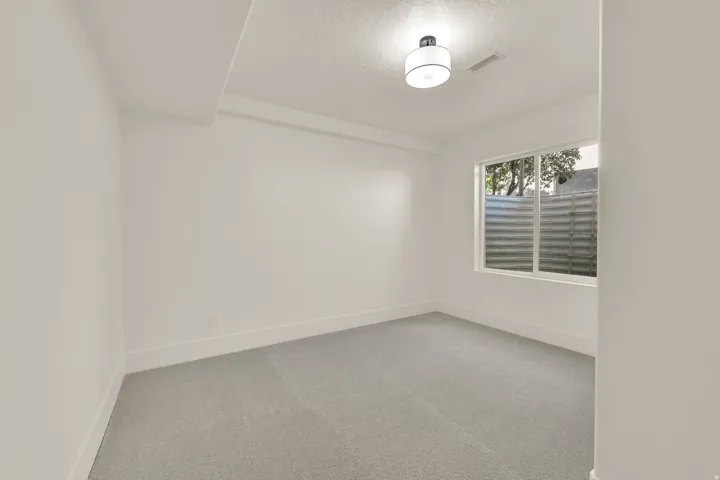 Recessed window with white trim, light gray wall-to-wall carpeting, and a flush-mount ceiling light