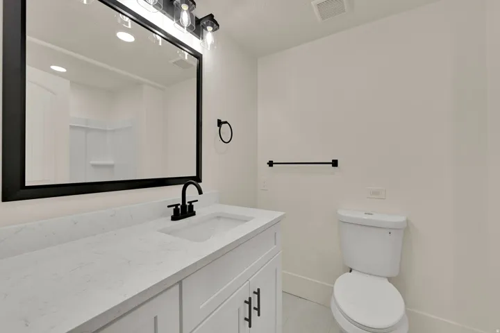 White vanity with shaker-style cabinetry, a white countertop, and an integrated rectangular sink