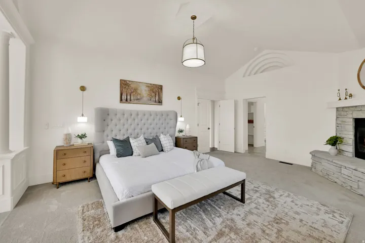 Primary Suite with vaulted ceiling, stone fireplace, recessed lighting, double doors, and a built-in architectural detail