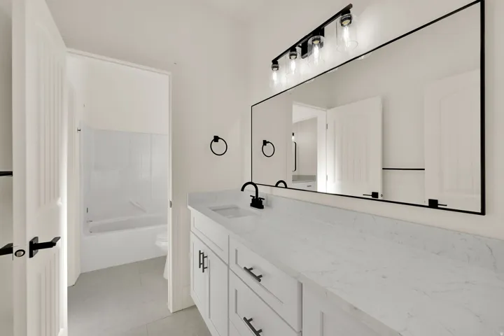 Double vanity with white cabinetry and integrated sinks, complemented by matte black hardware and a full-width mirror