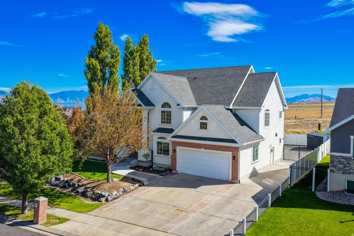 Two-story residence with a dark shingle roof, white stucco exterior, and red brick accents