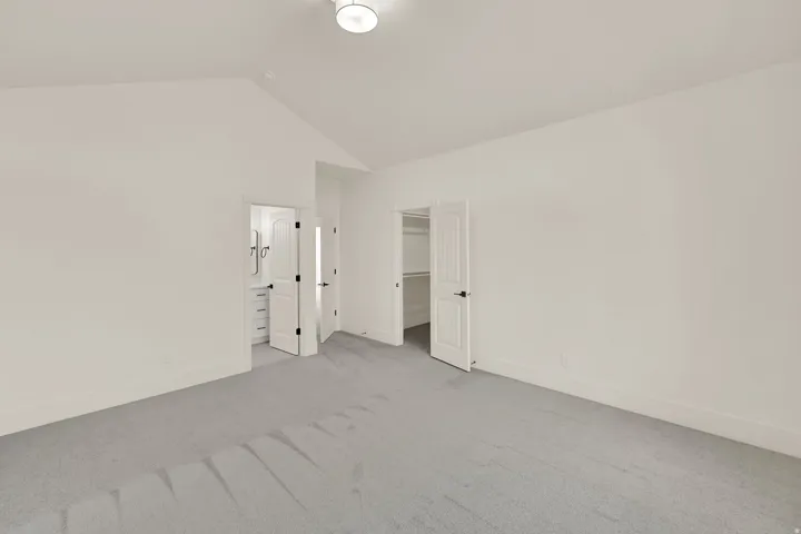 Vaulted ceiling room with light gray carpeting, white walls, and a contemporary ceiling light fixture