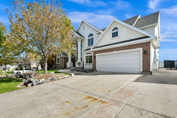 Stucco and brick exterior with arched windows, a two-car garage, and a concrete driveway