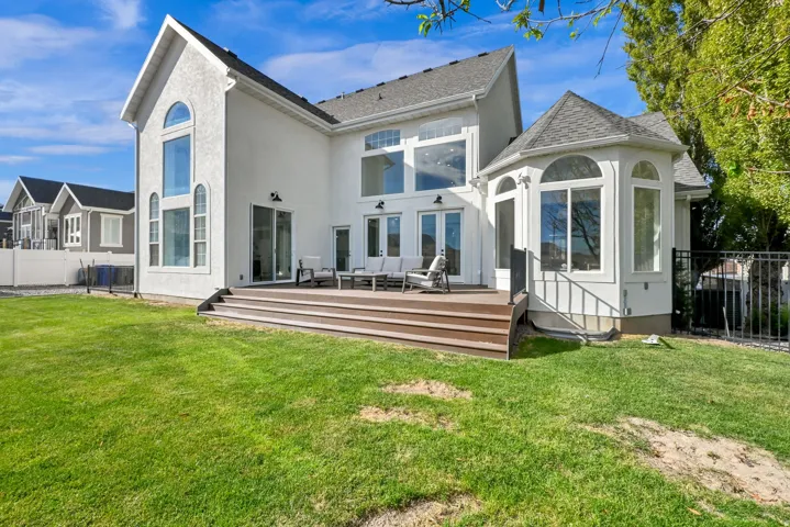 White stucco exterior, composite decking, multiple large windows, bay window feature, black metal fencing