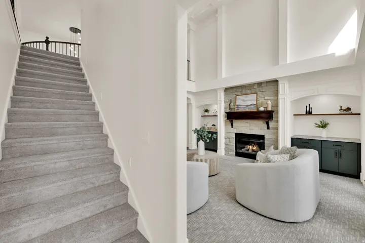 Two-story living area with a stone-clad fireplace and wood mantel, complemented by built-in cabinetry and shelving