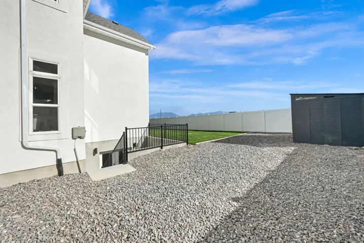 White stucco exterior with a black metal handrail and window well