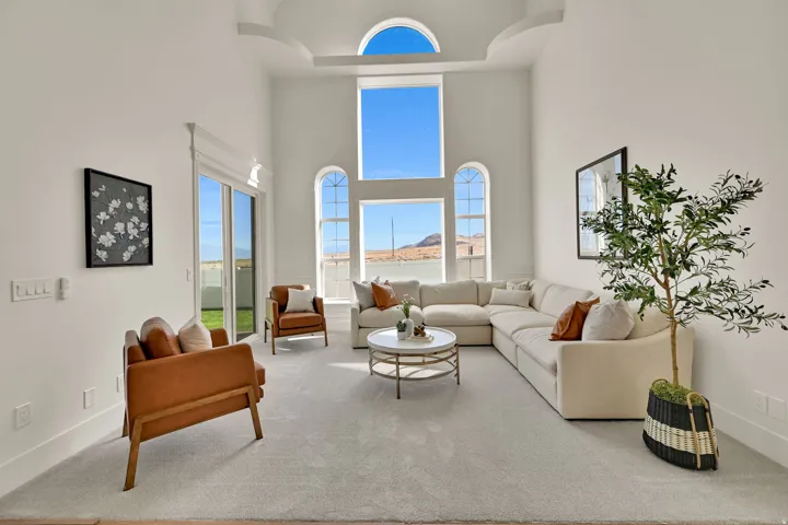 Two-story vaulted ceiling with arched windows, carpeted flooring, sliding glass door, and coved ceiling detail