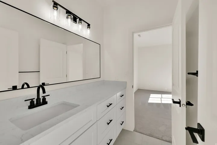 Double vanity with integrated sink, white cabinetry, and matte black hardware