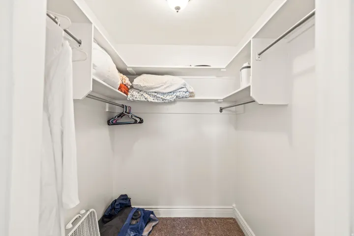 Walk-in closet featuring white shelving and hanging rods