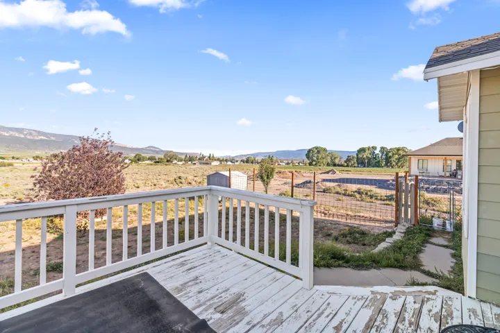 Exterior deck with white railing, featuring expansive distant mountain scenery