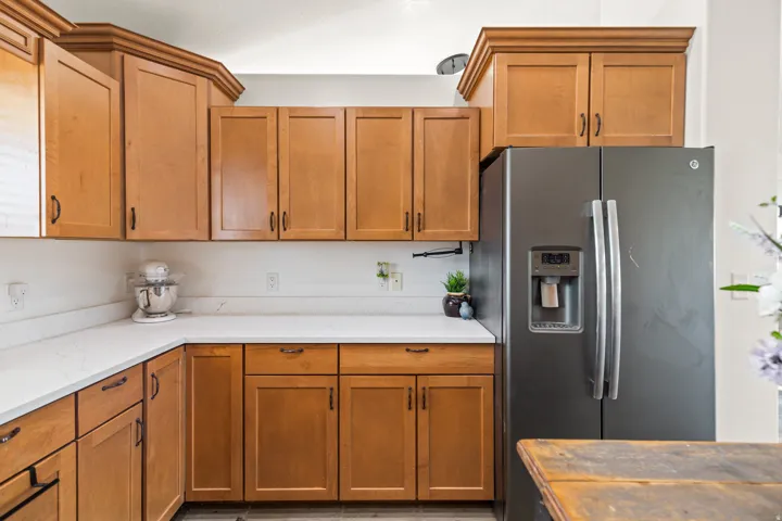 Kitchen featuring light wood-finish cabinetry, white countertops, and a full-size stainless steel refrigerator