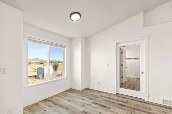 Wood-finish flooring, white walls, and a large window with a distant mountain backdrop