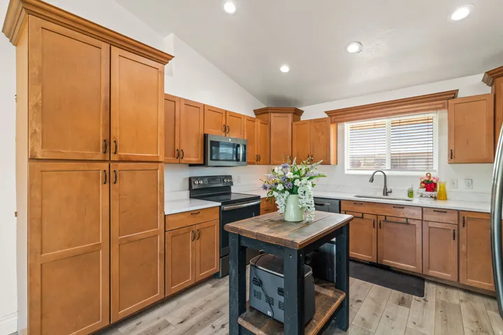 Kitchen featuring wood-finish cabinetry, white countertops, stainless steel appliances, and wood-finish flooring