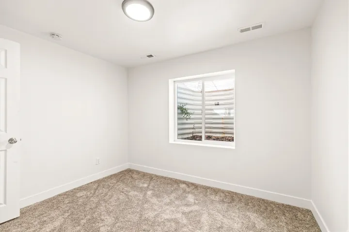 Neutral-toned carpeting, white painted walls, and a recessed ceiling light fixture