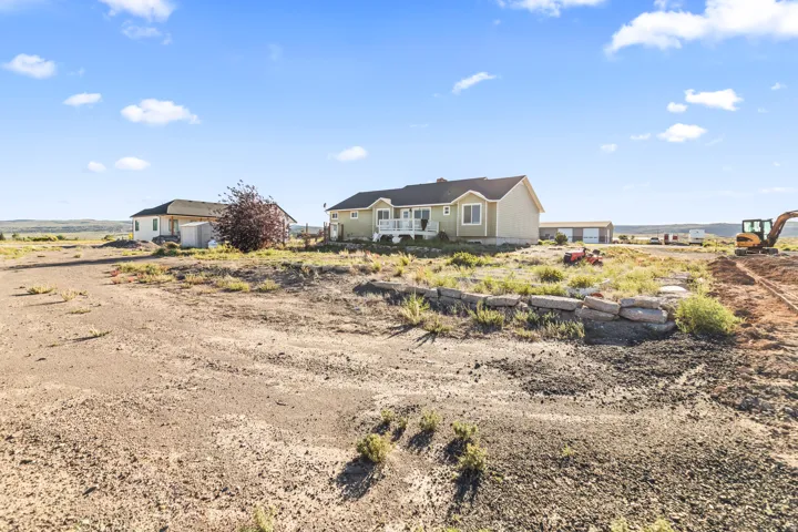Expansive lot featuring a main residence with a covered porch, a secondary dwelling, and multiple outbuildings