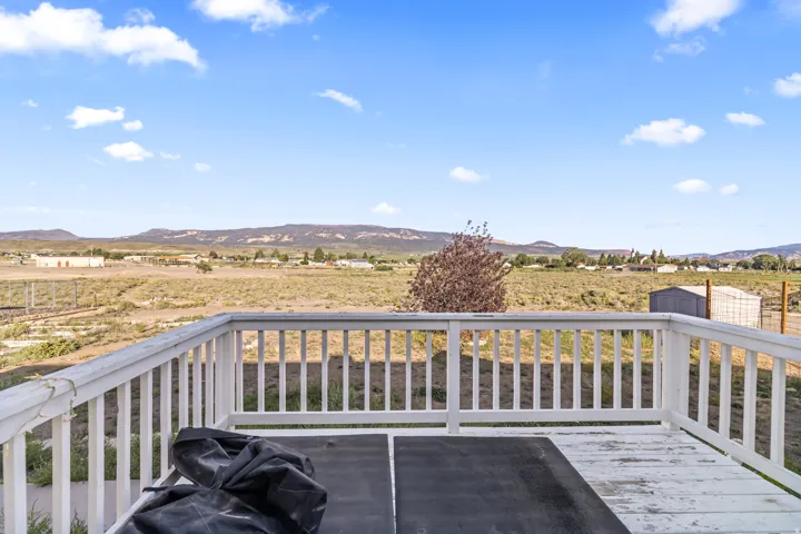 Expansive outdoor deck with a white railing system, offering distant mountain scenery