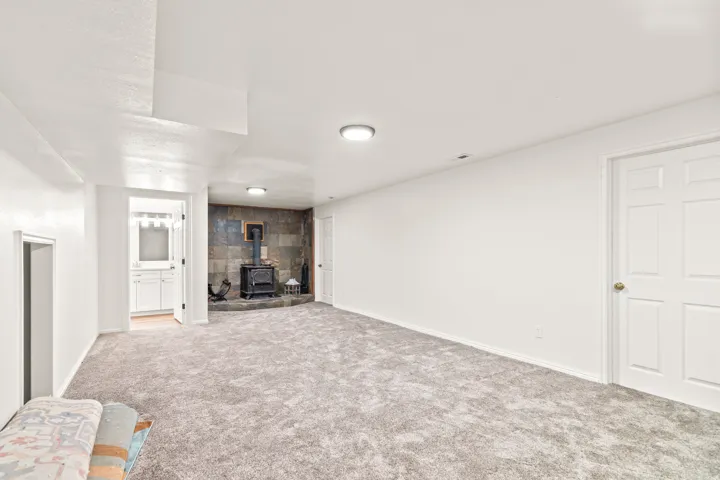 Spacious room with gray carpeting, an accent wall with stone-finish tiles, and a freestanding wood-burning stove