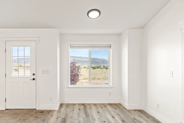 Wood-finish flooring, white trim, recessed lighting, and a white paneled door with glass inserts
