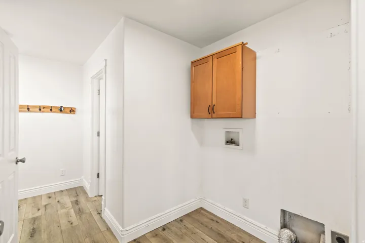 Wood-finish flooring, white trim, and a wall-mounted wooden cabinet