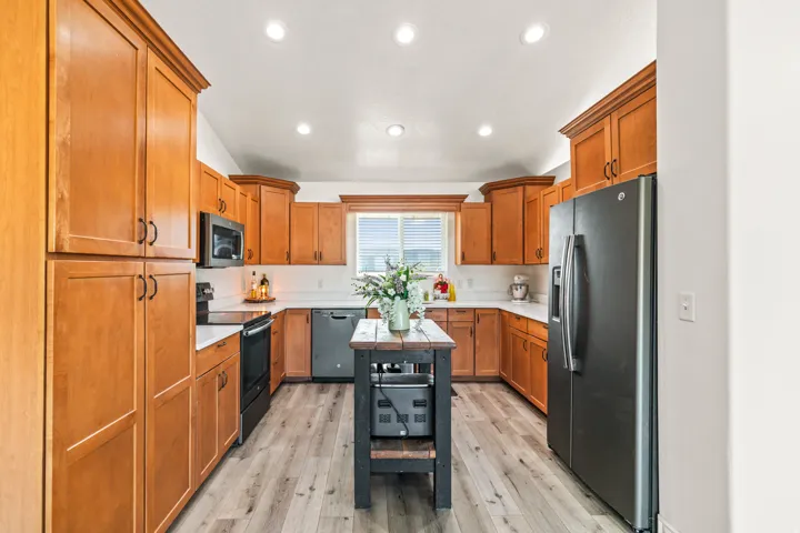 Kitchen featuring wood-finish cabinetry, white countertops, built-in microwave, integrated dishwasher, and wood-finish flooring