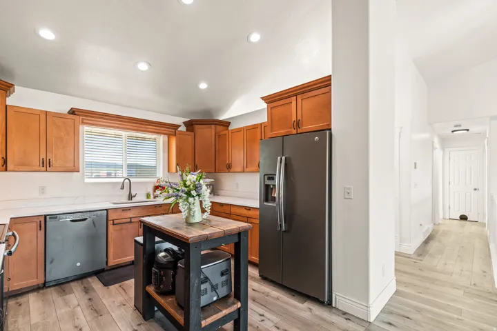 Hardwood-finish flooring, recessed lighting, wood cabinetry, white countertops, and stainless steel appliances