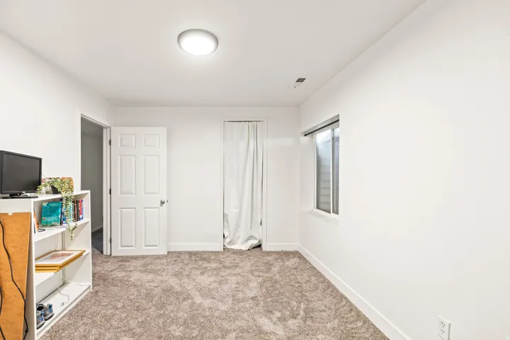 Neutral paint palette with plush carpeting, a single window, and a flush-mount ceiling light