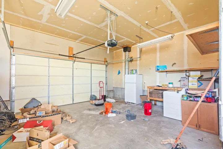 Attached garage with concrete flooring, overhead fluorescent lighting, and built-in shelving