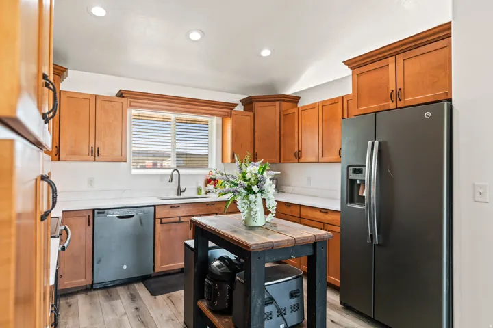 Kitchen featuring wood-finish cabinetry, light countertops, wood-finish flooring, a stainless steel sink, and recessed lighting