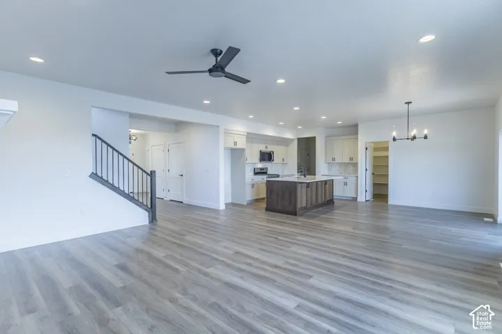 Open-concept living area with light wood-finish flooring, recessed lighting, and a modern ceiling fan