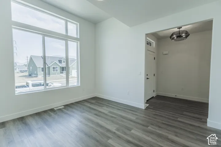 Spacious room with large multi-pane windows, wood-finish flooring, white walls, and a modern ceiling fixture in the entryway