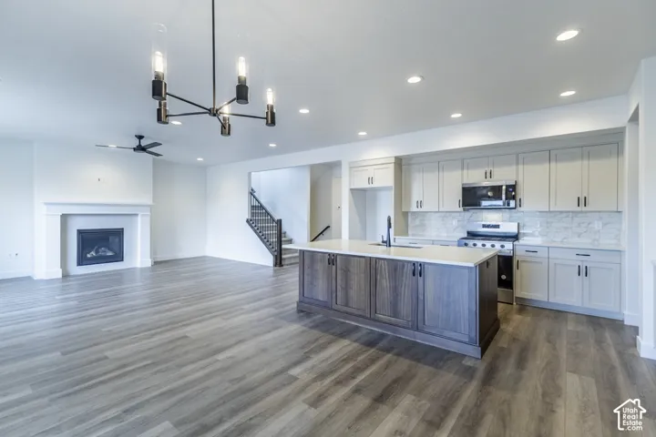 Open-concept living space featuring wood-finish flooring, a contemporary fireplace, a modern chandelier, and a kitchen island with built-in cabinetry