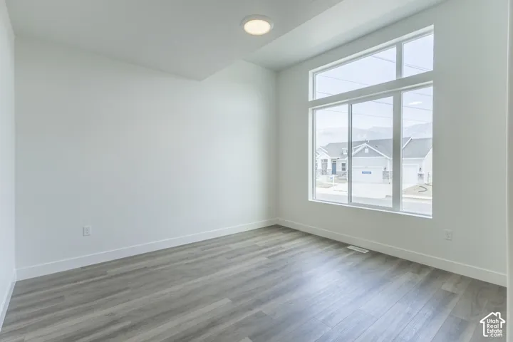 Expansive window arrangement with transom, recessed ceiling lighting, light wood-finish flooring, and crisp white walls