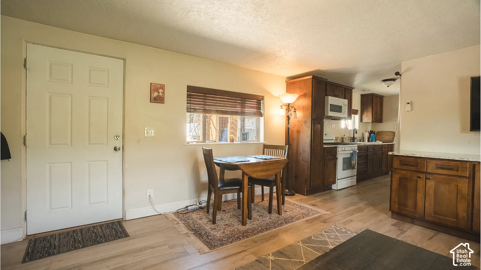Wood-finish flooring throughout, kitchen with wood cabinetry, and white appliances