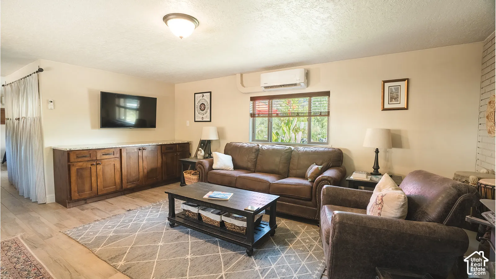 Integrated cabinetry with a light-toned countertop, wood-finish flooring, and a wall-mounted climate control unit