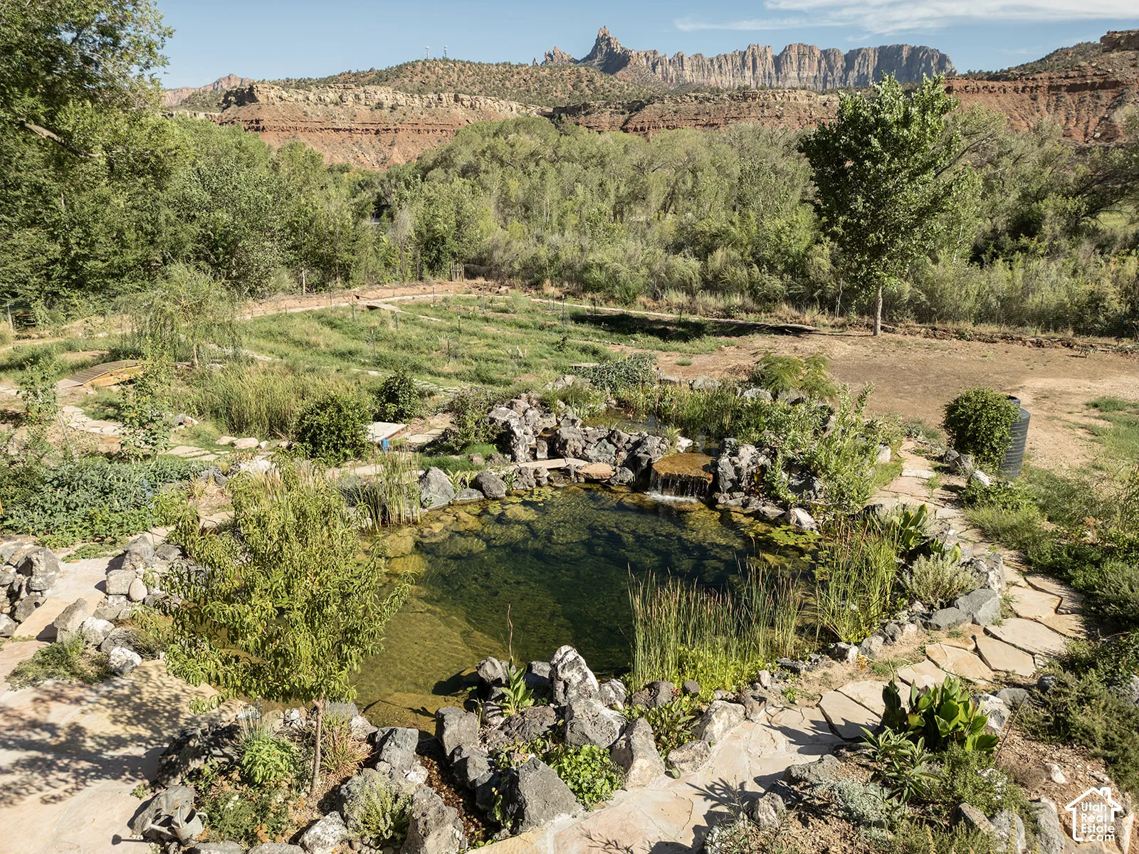 Natural water feature with rock surround, flagstone pathways, and established greenery