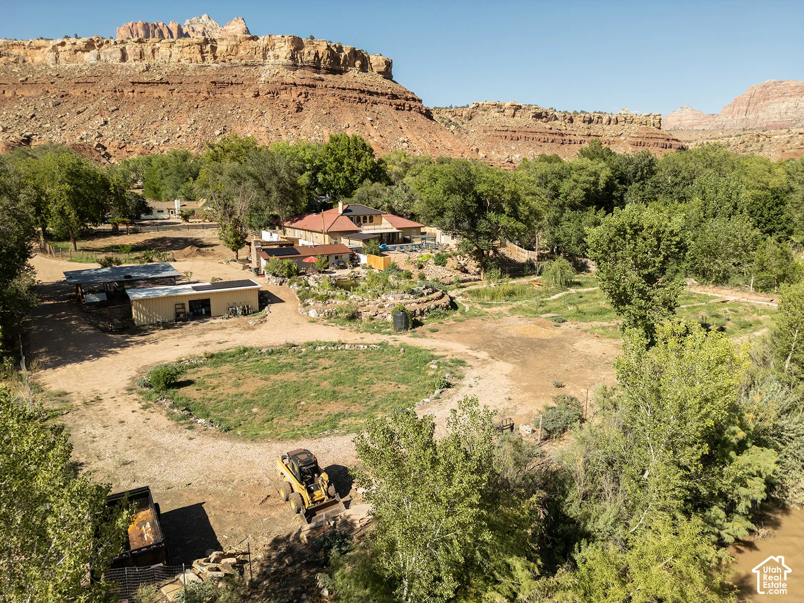 Southwestern-style architecture with a red tile roof, situated in a valley with mature trees