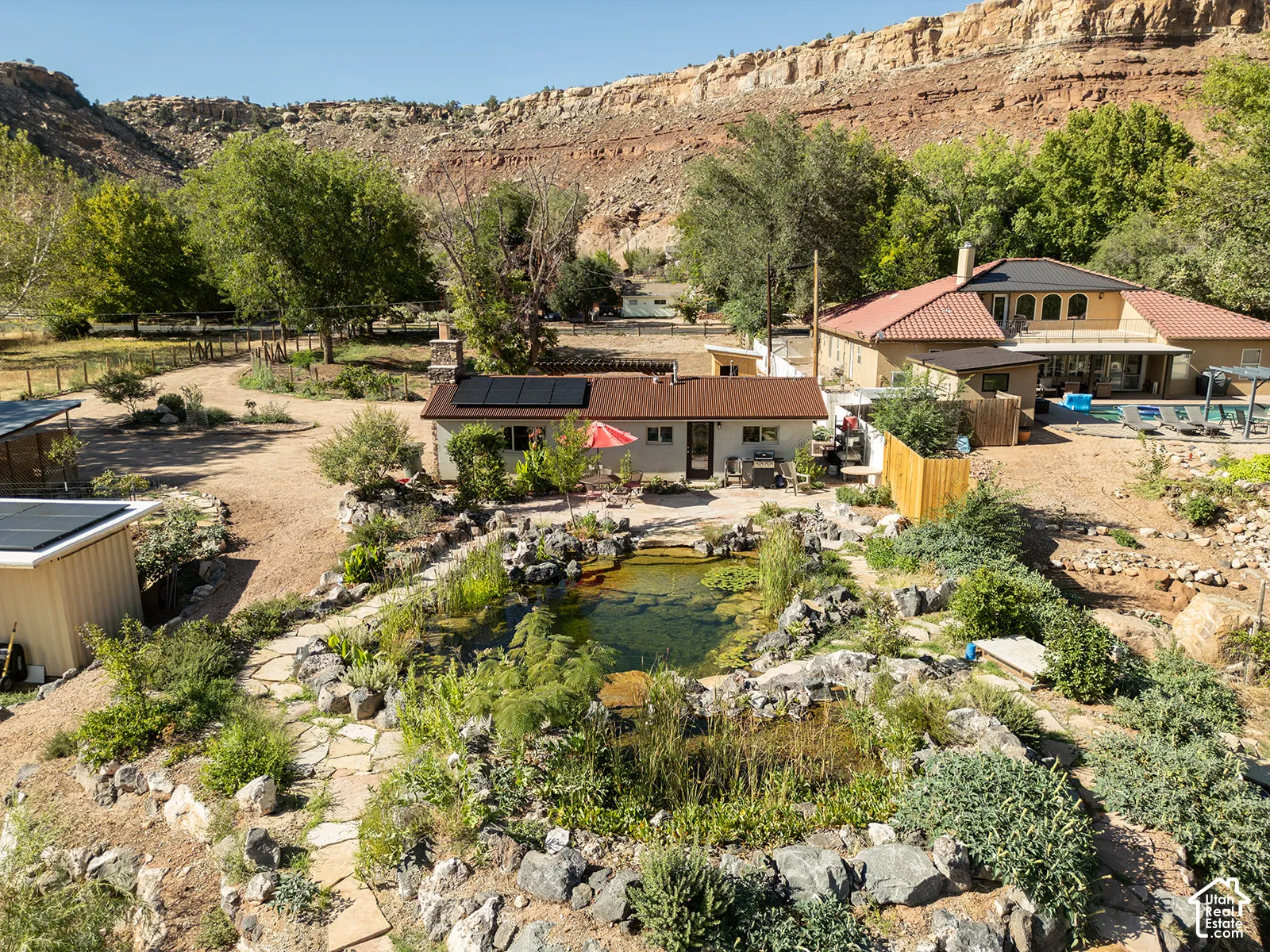 Terracotta roof, integrated solar panels, natural stone pathways, established landscaping, and a built-in outdoor pool