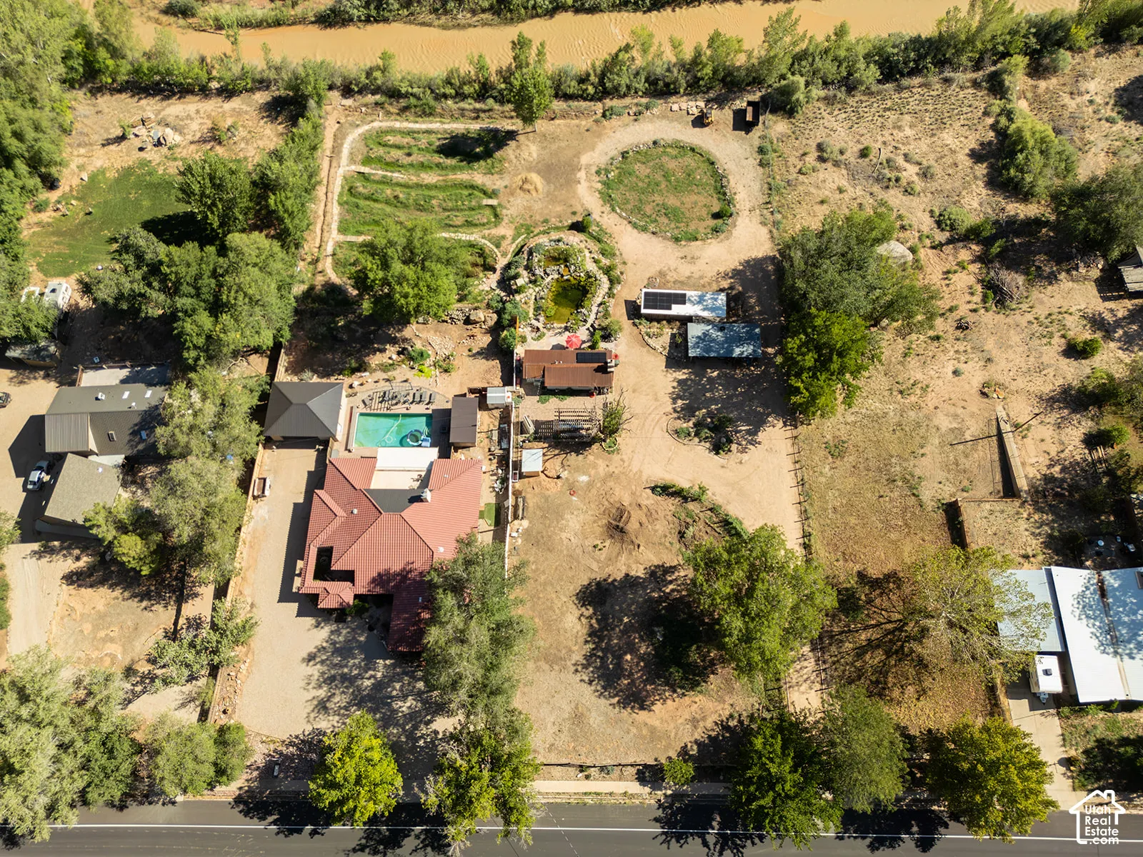 Property featuring a pool, surrounding patio, and multiple detached structures