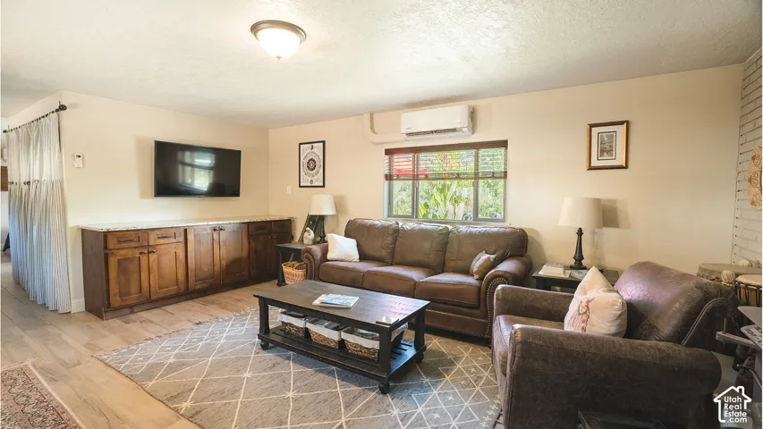Integrated cabinetry with a light-toned countertop, wood-finish flooring, and a wall-mounted climate control unit