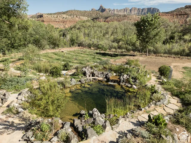 Natural water feature with rock surround, flagstone pathways, and established greenery