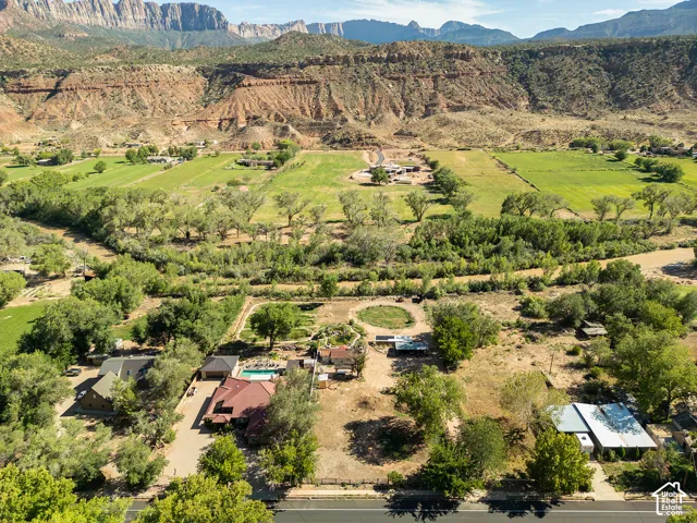 Expansive property featuring a private swimming pool, multiple residential structures, mature trees, and direct access to a paved road