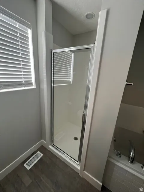 Glass-enclosed shower with a white base and silver-finish hardware