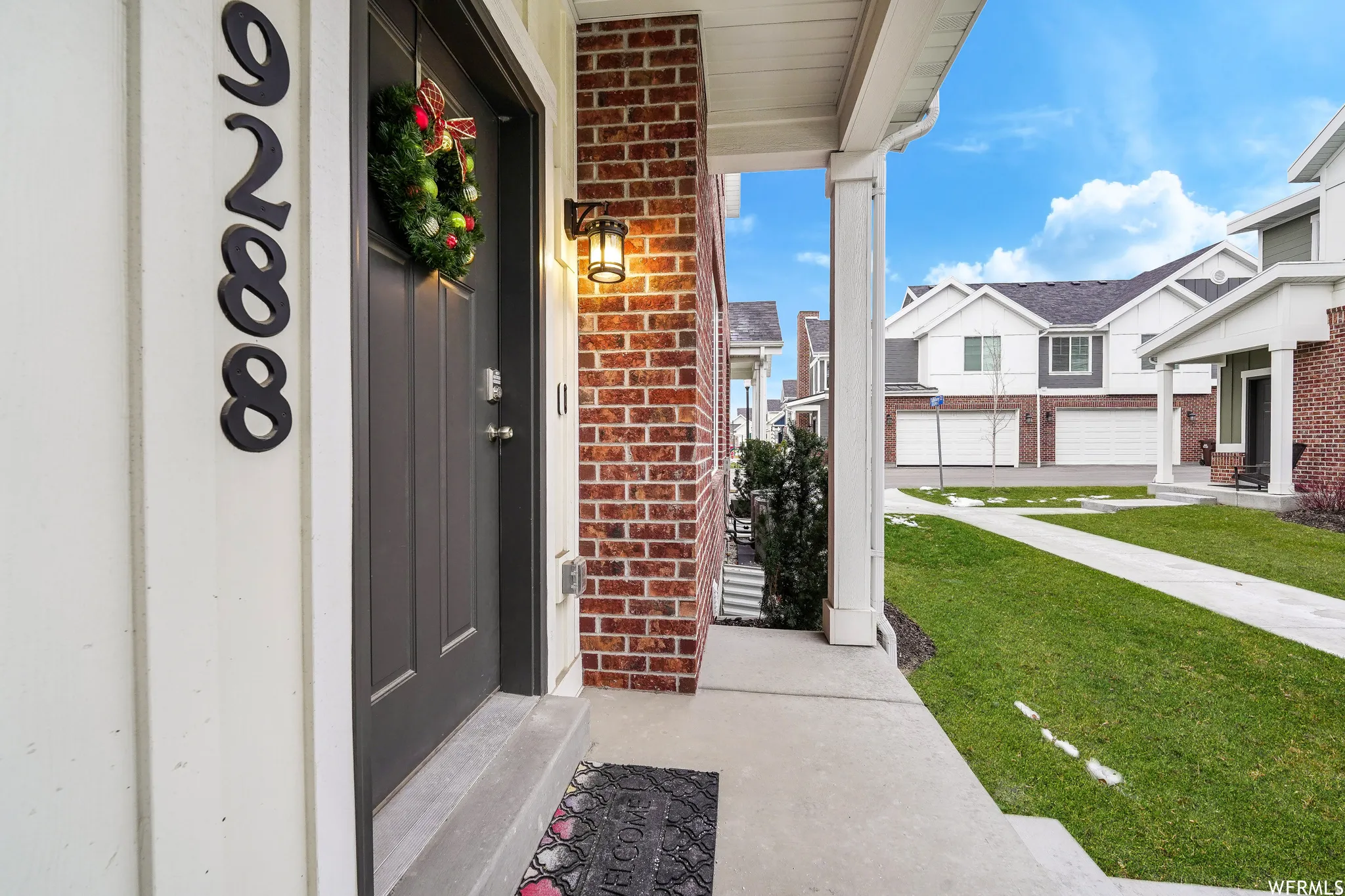 Inviting porch entry featuring a dark paneled door, brick façade, and white siding