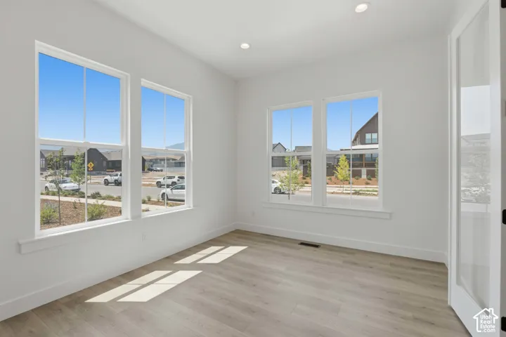 Recessed ceiling lighting, wood-finish flooring, multiple windows, white trim, and a clear glass paneled door