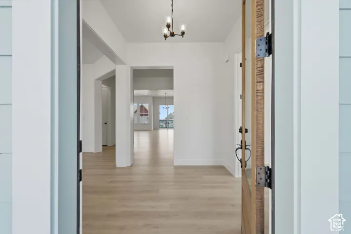 Open concept floorplan with wood-finish flooring, white walls, and a multi-light chandelier