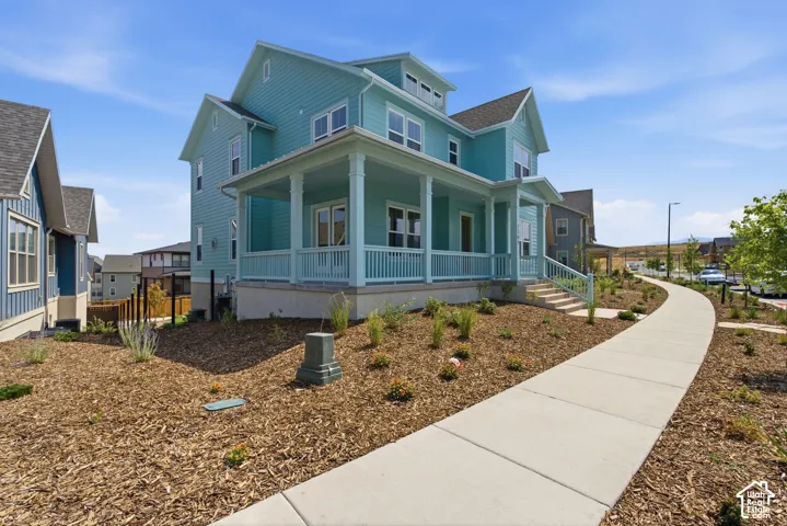 Charming farmhouse-style residence featuring a light blue exterior with white trim, wraparound covered porch, and gabled roofline