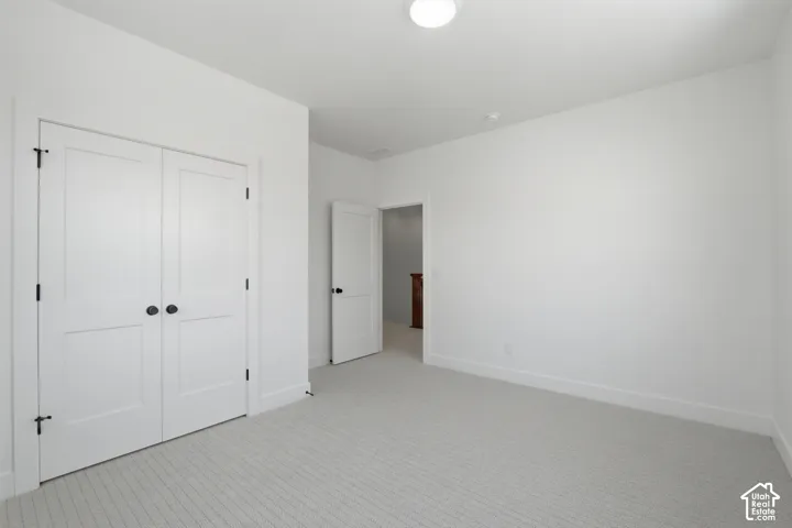 Recessed ceiling light, neutral wall paint, light-colored patterned carpeting, white interior doors with black hardware, and white trim